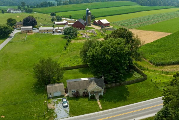Contact - Aerial View of Farmlands and a Rural Road in the Late Afternoon